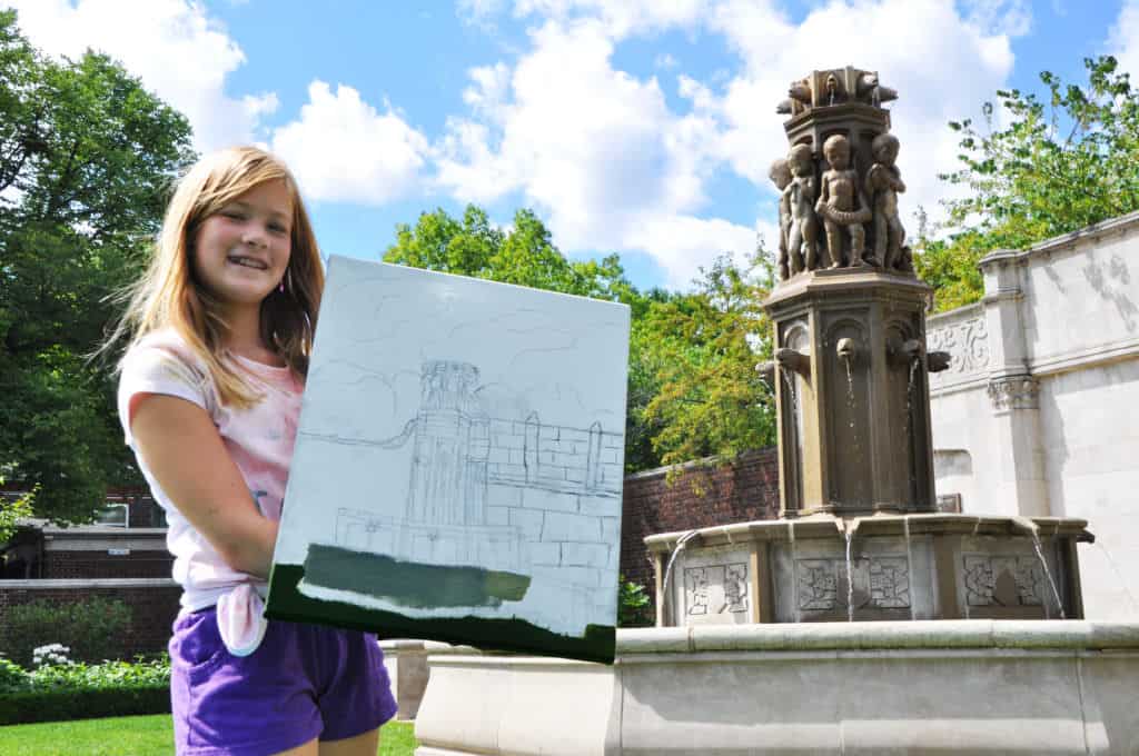 student holding a painting outside